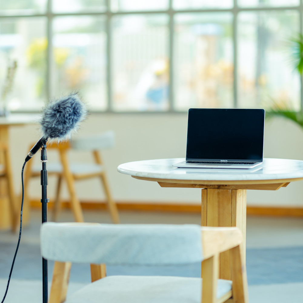 Laptop on table with microphone and empty chair