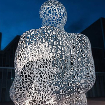 An unusual statue made from delicate metal strands, lit within on at dusk