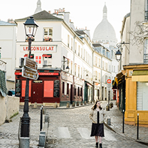 A dreamy, pale image of a girl walking down a cobbled street in Montmartre