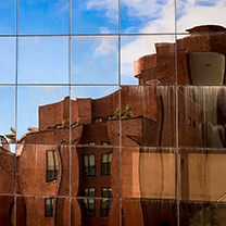 The reflection of a red stone building, the mirror is cut into a grid which distorts the reflection with a very pleasing pattern