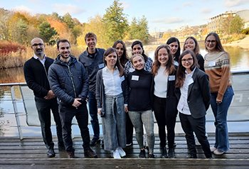 A group of PhD researchers standing on the boardwalk outside the Jubilee Conference centre with the lake in the backgroundCTP-Students-Nov23x350x238