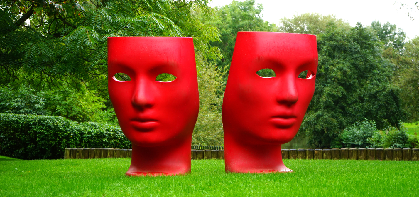 Red Human Face Monument on Green Grass Field