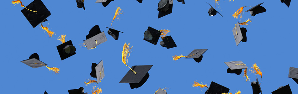 Blue sky with multiple graduation caps that have been thrown in the air