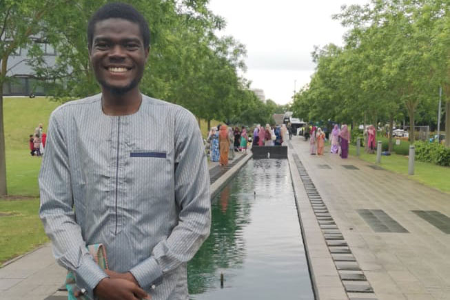 Abdullah Akolade stood in front of a river in a park