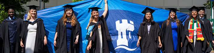 students walking at graduation holding university banner