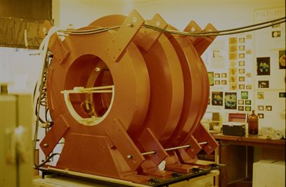 Colour photo of large red torus-shaped magnet coils, on a laboratory bench.  This image is from the papers of Brian Worthington, held by Manuscripts and Special Collections.  Document reference PBW/12/24.