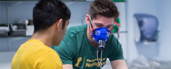 Athlete exercising with a breathing mask on while students observe