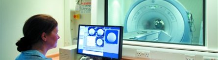 Female radiographer checking results of MRI scan in hyperpolorisation imaging facility