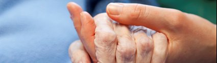 Carer holding hand of elderly patient