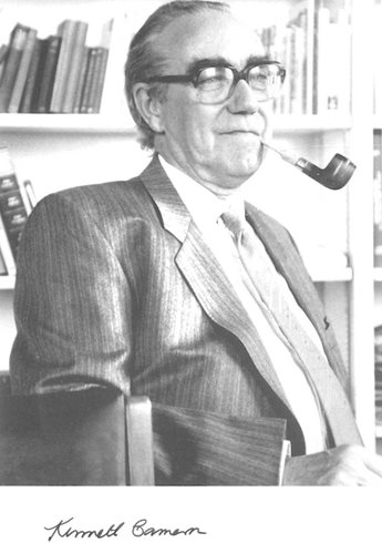 Black and white photograph of an older white man wearing glasses, a suit and smoking a pipe.