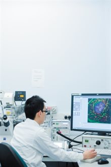 A male PhD student working at a microscope