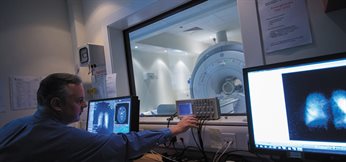 Dr Brett Haywood operating the GE 1.5 Tesla MRI machine from a computer - Medical School, QMC