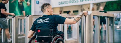 Student in wheelchair passes turnstiles at David Ross Sports Village