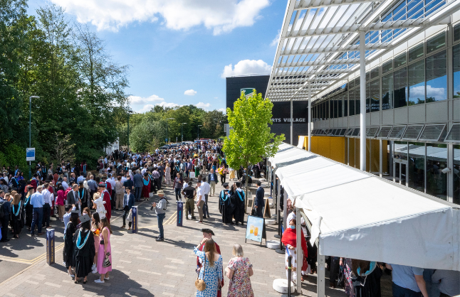 Photograph of a large group of graduating students and guests outside David Ross Sports Village, University Park Campus