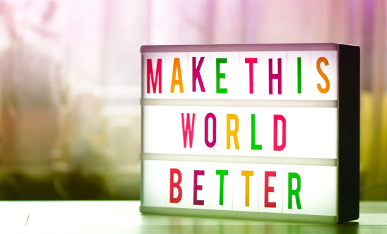 Illuminated sign on desk saying "Make this world better" in coloured letters