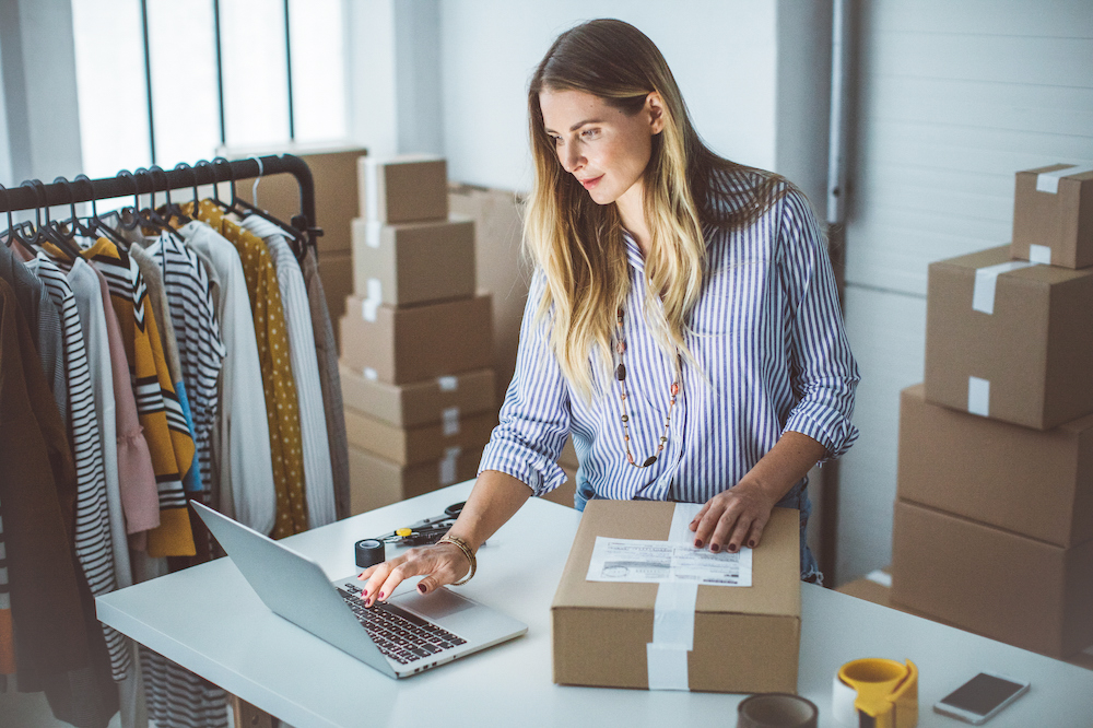 Self employed woman is packing products into boxes in home office