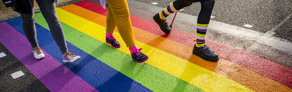 The feet of three students walking over a rainbow crossing on University Park campus