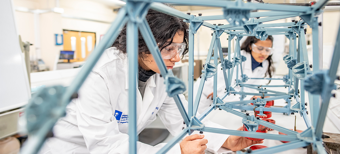 Students in an engineering lab looking at a design model of a metal bridge