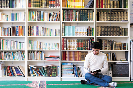 Male student studying in front of a wall of books