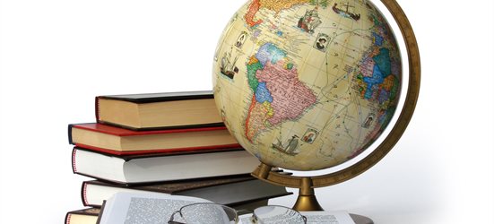 Globe and pile of books against a white background