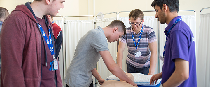 Summer school students practising CPR on a mannequin