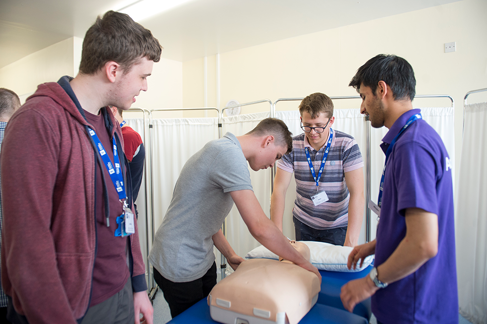 Summer school students practising CPR on a mannequin