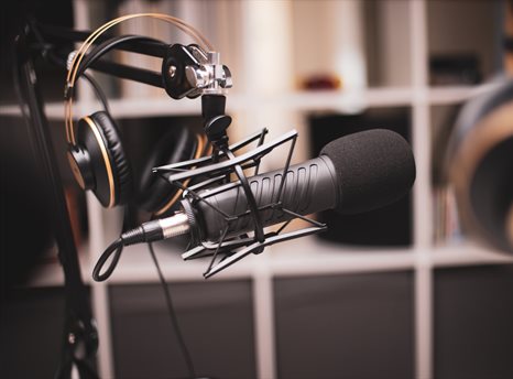Side on shot of a podcasting set-up with headphones and a professional microphone