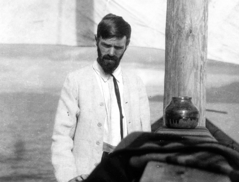 Black and white photograph of a white man (D H Lawrence) with a beard in a white suit.