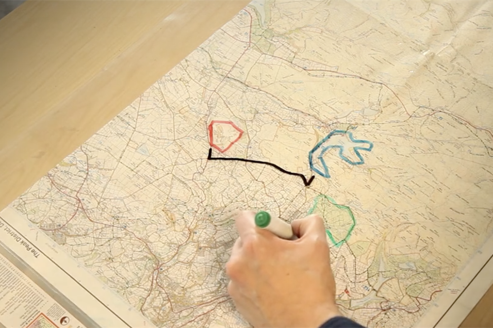 A person drawing on a map, which is part of the Augmented Bird Table