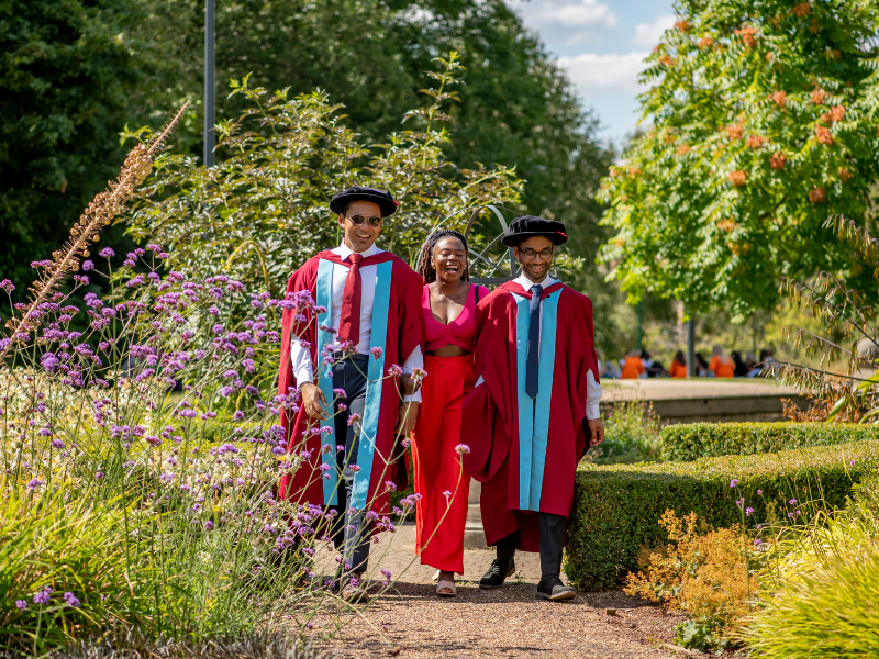 Photograph of three people walking through campus