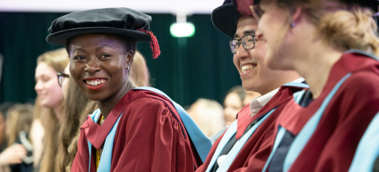Postgraduate student's smiling at the camera during their graduation ceremony