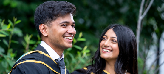 Two graduating student's smiling outside