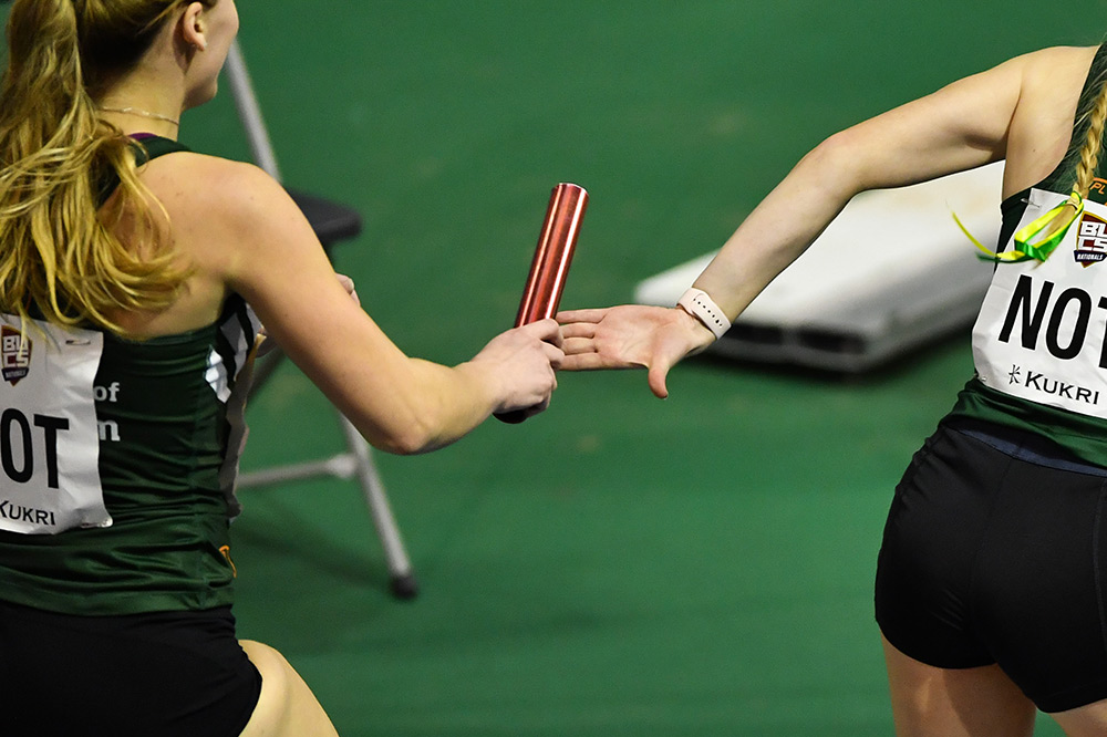 Two female students pass the baton in a relay race