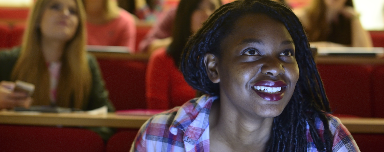 Black student sitting at front of lecture room, smiling