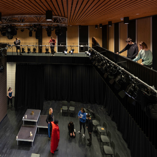 Students rehearsing play while other students look down from balcony in Monica Partridge performance space