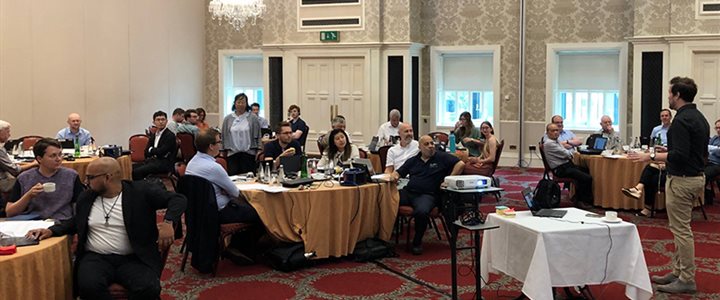 People sat at tables in a function room for a presentation during an Executive Education delivered progtramme