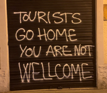 Photo of a sign saying 'Tourists go home, you are not welcome'