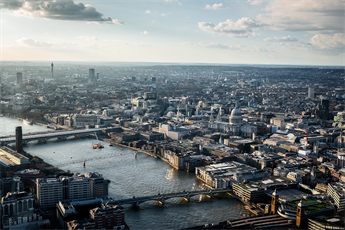 Arial photo of London showing the river Thames and surrounding city landscape of buildings and bridges..