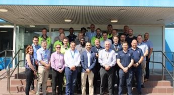 Delegates from the Uniper programme stand with Nick Proverbs, from the Executive Education team, outside the training facility. There are 29 people, 28 of whom are male. It is a sunny day and they are smiling at the camera.