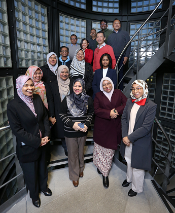 Malaysian attendees at the Empowering Public Sector Leaders programme, standing on a spiral grey metal stairwell with glass blocks