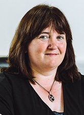 Head and shoulders photo of Wendy Furness. endy has shoulder length dark hair and is wearing a dark top. She is wearing a necklace with a dark pendant.