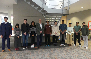 Students on the Sustainability and Societal Impact Fellows Programme with Prof David Park standing in front or metal stairs in the atrium of Business School South building