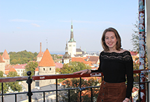 Kathryn stands, smiling, on a balcony in Russia with a church in the background