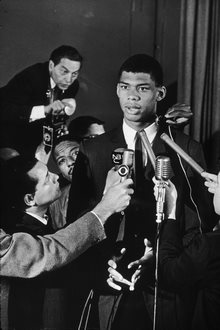 A black and white photo of Kareem Abdul-Jabbar, one of the subjects of Alex Riggs&amp;#39; essay, speaking into microphones