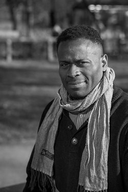 Black and white photo of Onyeka Nubia, standing outside and wearing a scarf