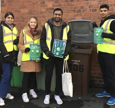 Students promoting please no more bags campaign in front of a wheelie bin