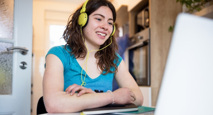 Female student with headphones in front of a laptop talking to someone online