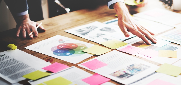 Person with a desk full of papers and post-it notes in an office environment