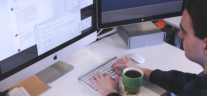 Man looking at multiple computer screens while working