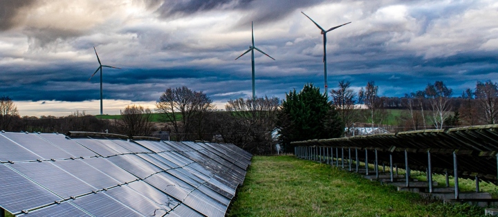 Solar panels with wind towers in the background